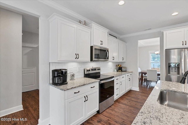 kitchen with stainless steel appliances, a sink, dark wood-style flooring, white cabinetry, and ornamental molding
