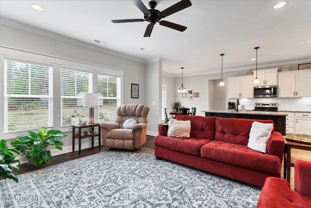living room featuring wood finished floors, baseboards, a ceiling fan, recessed lighting, and crown molding
