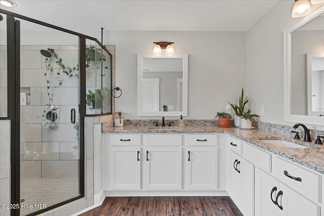 bathroom with a stall shower, wood finished floors, and double vanity