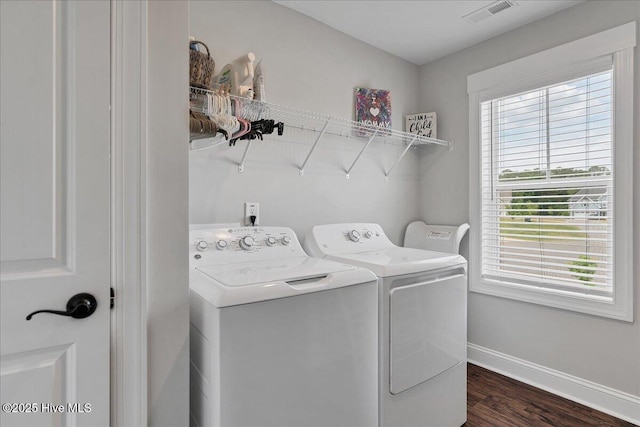 laundry area featuring washer and dryer, healthy amount of natural light, baseboards, and dark wood-type flooring