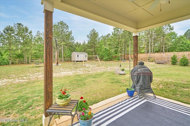 view of patio featuring a storage unit, an outbuilding, a ceiling fan, and view of scattered trees