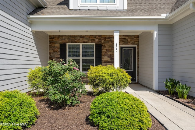 365 W Goldeneye Ln, Sneads Ferry, NC 28460 - doorway to property featuring a shingled roof, stone siding, and covered porch