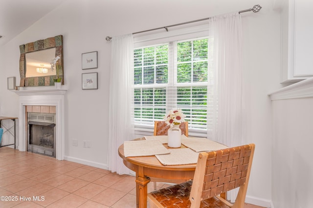 dining room featuring light tile patterned floors, baseboards, a fireplace, and plenty of natural light