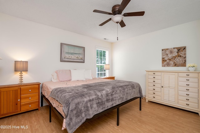 bedroom with light wood finished floors, visible vents, and a ceiling fan