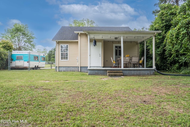 back of house featuring fence, a shingled roof, and a lawn