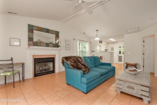living area featuring a tile fireplace, visible vents, ceiling fan, and light tile patterned flooring