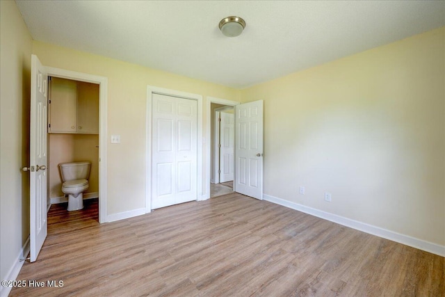 unfurnished bedroom with light wood-type flooring, a closet, and baseboards