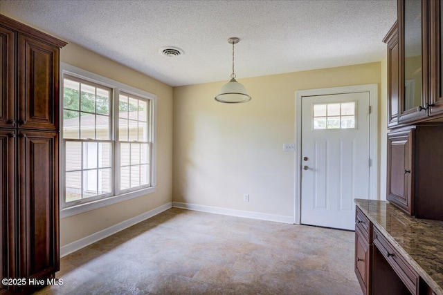 unfurnished dining area with healthy amount of natural light, baseboards, and a textured ceiling