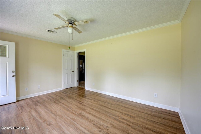 empty room with wood finished floors, a textured ceiling, ceiling fan, crown molding, and baseboards