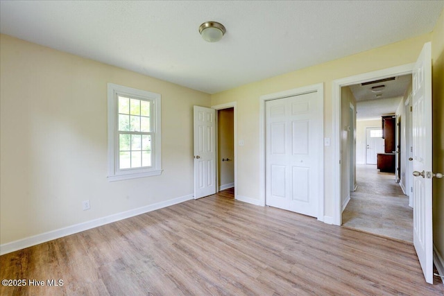 unfurnished bedroom featuring light wood finished floors, a closet, and baseboards