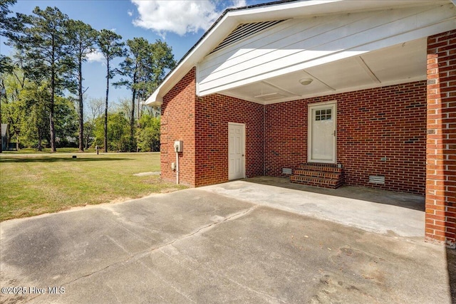 view of home's exterior with entry steps, a carport, a yard, brick siding, and concrete driveway