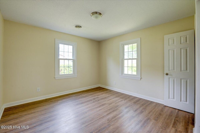 unfurnished room featuring plenty of natural light, wood finished floors, and baseboards