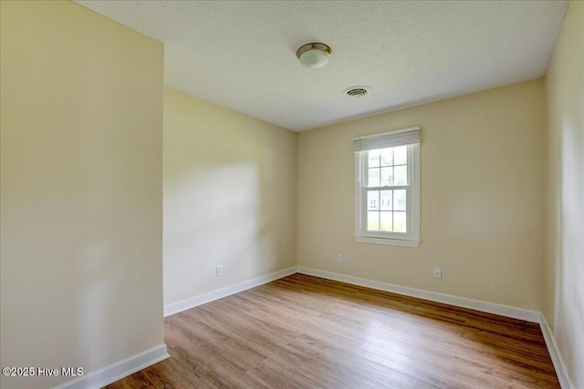empty room with wood finished floors, baseboards, and a textured ceiling
