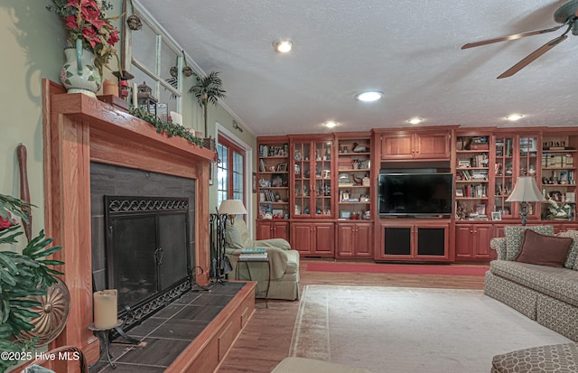 1 Collett Ln, Pinehurst, NC 28374 - living room with light wood-style floors, a tiled fireplace, a ceiling fan, a textured ceiling, and recessed lighting