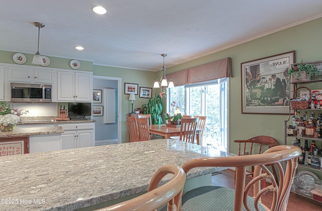 1 Collett Ln, Pinehurst, NC 28374 - kitchen with stainless steel microwave, white cabinetry, a chandelier, wood finished floors, and ornamental molding