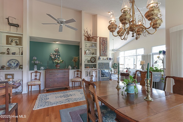 12 Shenecossett Ln, Pinehurst, NC 28374 - dining area with a ceiling fan, high vaulted ceiling, a glass covered fireplace, wood finished floors, and a chandelier