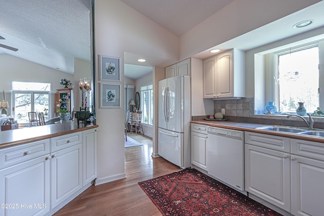 12 Shenecossett Ln, Pinehurst, NC 28374 - kitchen featuring white appliances, lofted ceiling, backsplash, wood finished floors, and white cabinetry