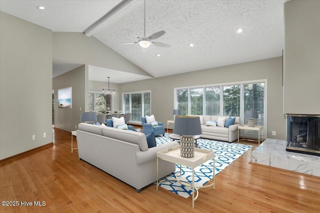 living area with beamed ceiling, wood finished floors, ceiling fan, high vaulted ceiling, and baseboards