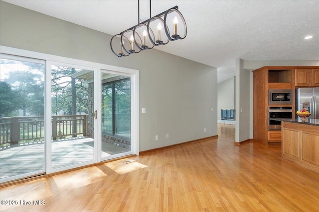 unfurnished dining area featuring light wood-type flooring, baseboards, recessed lighting, a textured ceiling, and a chandelier