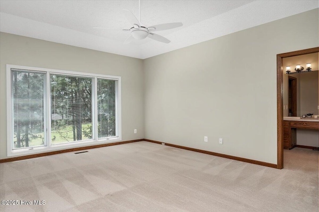 empty room with light colored carpet, baseboards, and ceiling fan