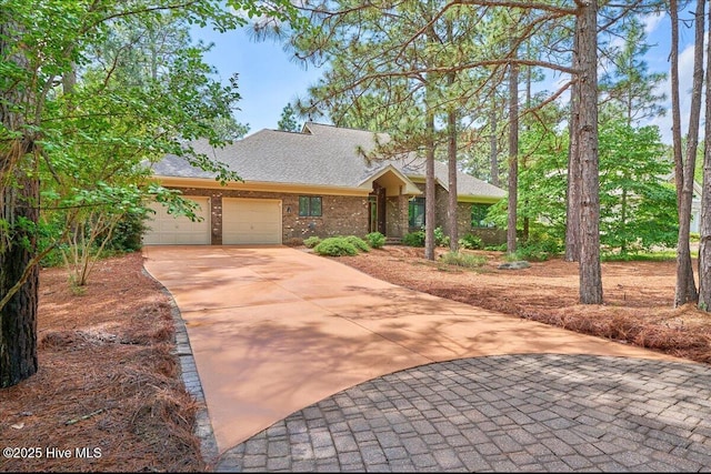 view of front facade featuring concrete driveway, an attached garage, roof with shingles, and brick siding