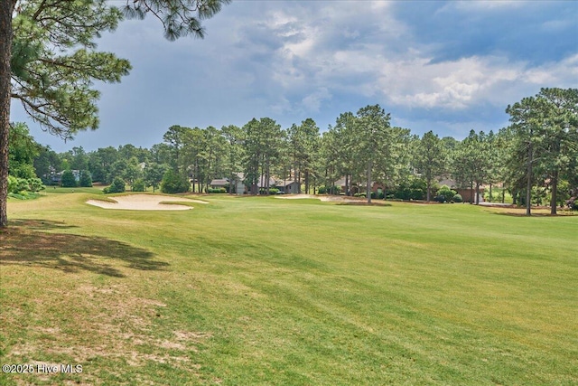 surrounding community with a yard, view of golf course, and view of wooded area