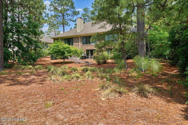 back of property with a chimney and brick siding
