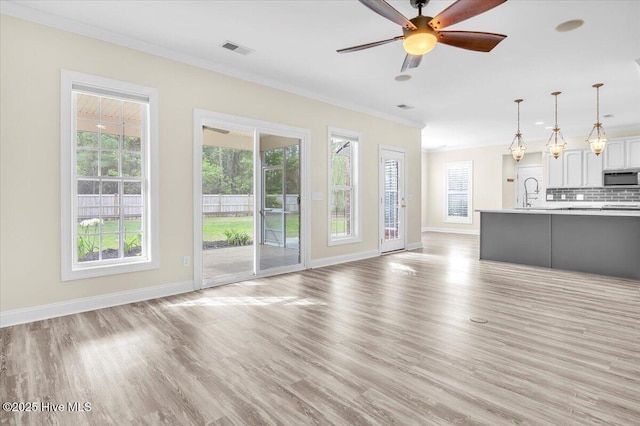 unfurnished living room with baseboards, light wood-type flooring, visible vents, and a ceiling fan