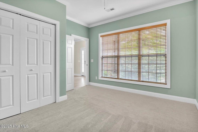 unfurnished bedroom featuring a closet, multiple windows, carpet, visible vents, and crown molding