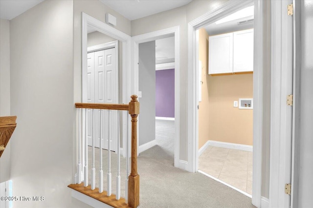 hallway featuring baseboards and light carpet