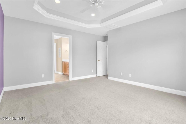 unfurnished bedroom featuring ensuite bathroom, recessed lighting, crown molding, carpet floors, and a tray ceiling