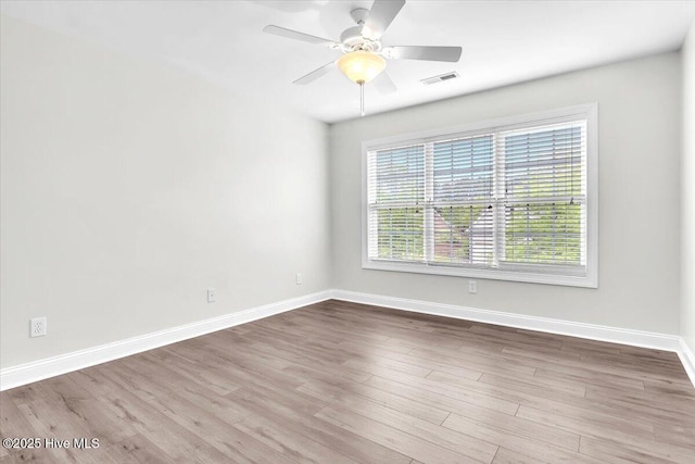 unfurnished room with baseboards, a ceiling fan, visible vents, and wood finished floors
