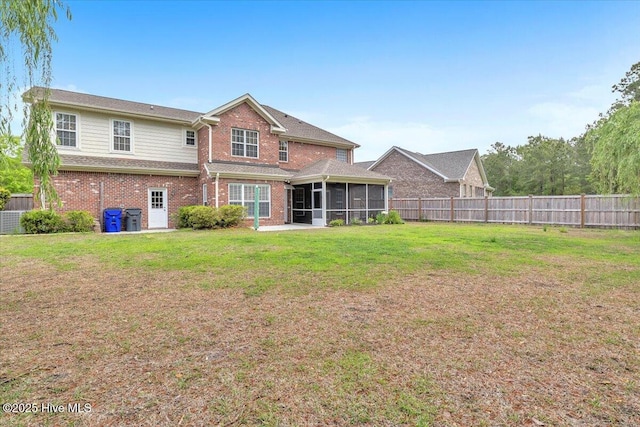 back of house with a fenced backyard, a sunroom, brick siding, and a lawn