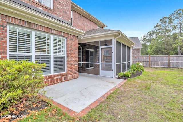 back of house featuring a lawn, brick siding, fence, a patio, and a sunroom