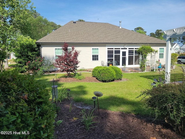 rear view of property with a shingled roof and a lawn