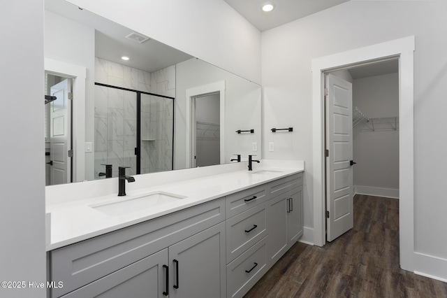 735 Hollybriar Loop Rd SE, Bolivia, NC 28422 - bathroom featuring double vanity, a shower stall, a walk in closet, wood finished floors, and baseboards