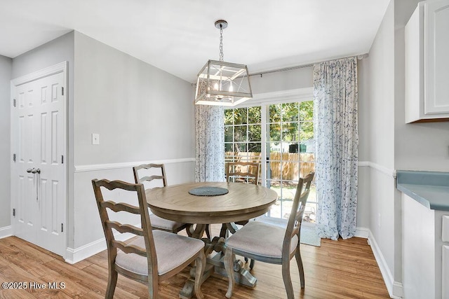 dining area featuring light wood-style flooring, baseboards, and a notable chandelier