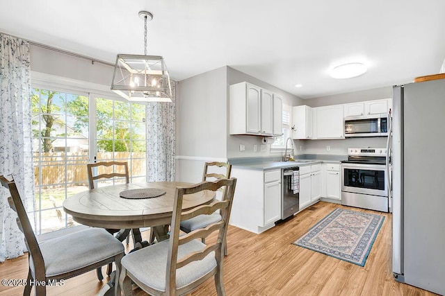 kitchen featuring a sink, light wood-style flooring, white cabinetry, light countertops, and appliances with stainless steel finishes