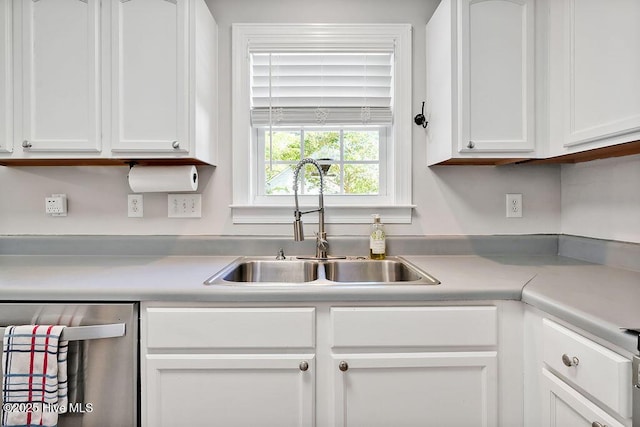 kitchen with light countertops, white cabinets, a sink, and dishwasher