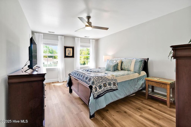 bedroom featuring light wood finished floors, visible vents, and ceiling fan