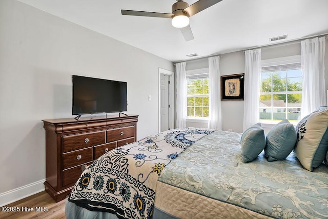 bedroom featuring multiple windows, visible vents, and wood finished floors
