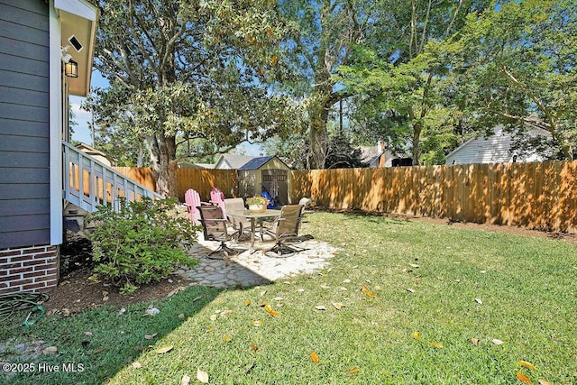 view of yard featuring an outdoor structure, a patio area, a fenced backyard, and a storage unit