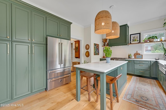 kitchen with high quality fridge, light countertops, green cabinets, and backsplash
