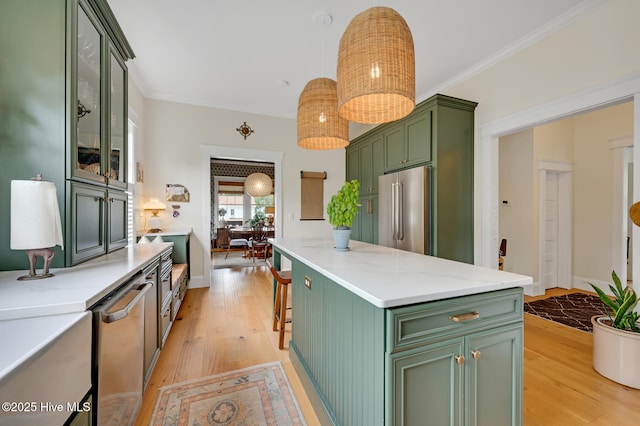 kitchen featuring a center island, decorative light fixtures, light wood finished floors, green cabinetry, and stainless steel appliances