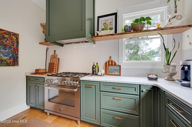 kitchen with backsplash, light countertops, stainless steel stove, and green cabinetry