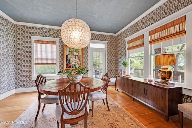 dining space with ornamental molding, light wood-style flooring, and wallpapered walls
