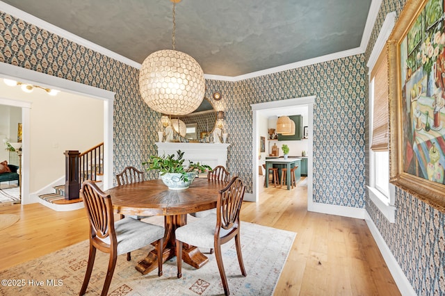 dining space with wallpapered walls, light wood-type flooring, ornamental molding, and stairs