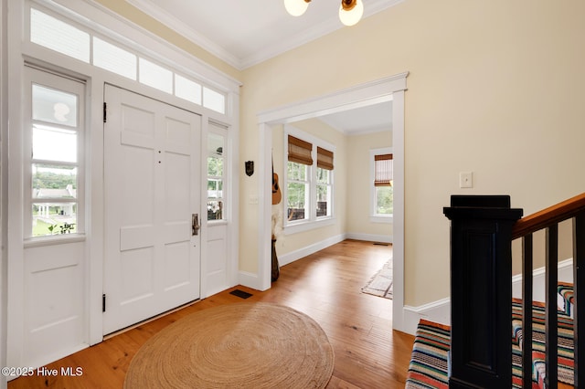 entrance foyer with ornamental molding, baseboards, visible vents, and wood finished floors