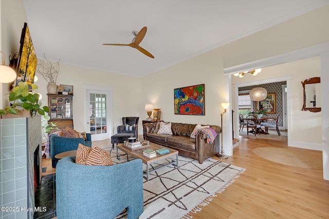 living room featuring baseboards, wood finished floors, ceiling fan with notable chandelier, and a healthy amount of sunlight