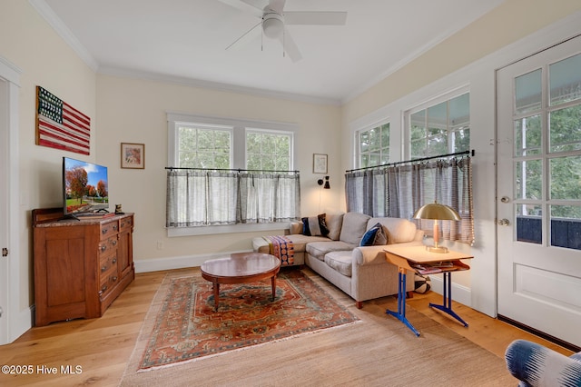 living room with a ceiling fan, crown molding, light wood-type flooring, and baseboards
